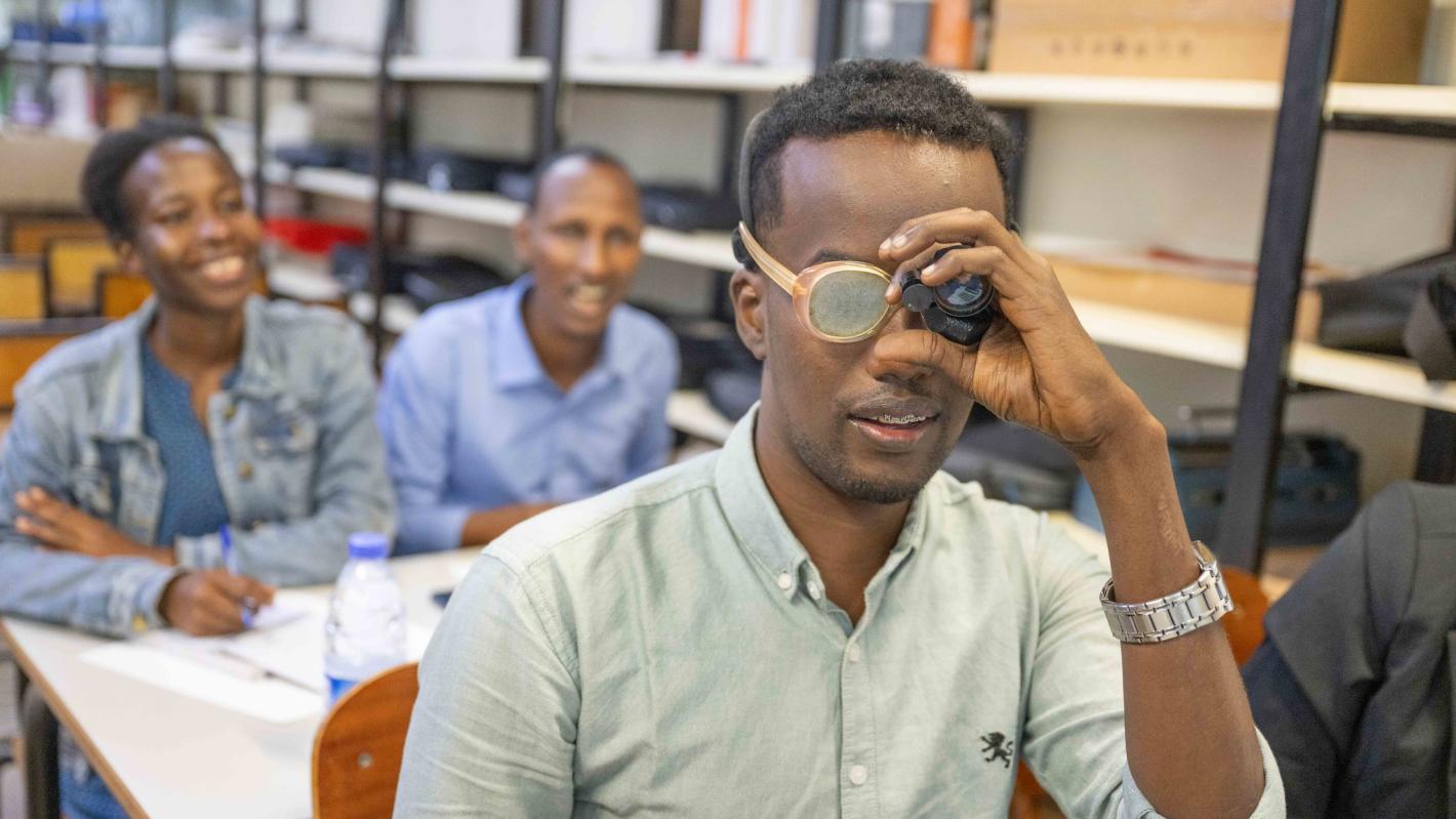 Photo of Mr. Kulane tries on a pair of low-vision glasses for the first time.