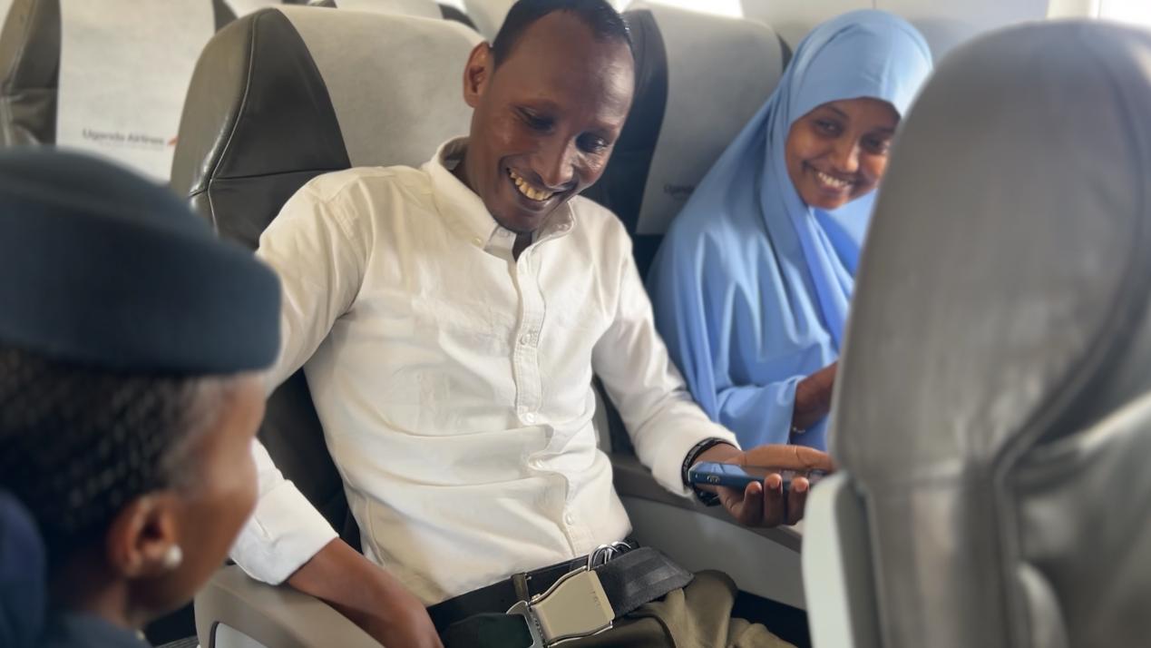 A photo of Mr. Abdullahi and Ms. Osman speaking with a flight attendant.