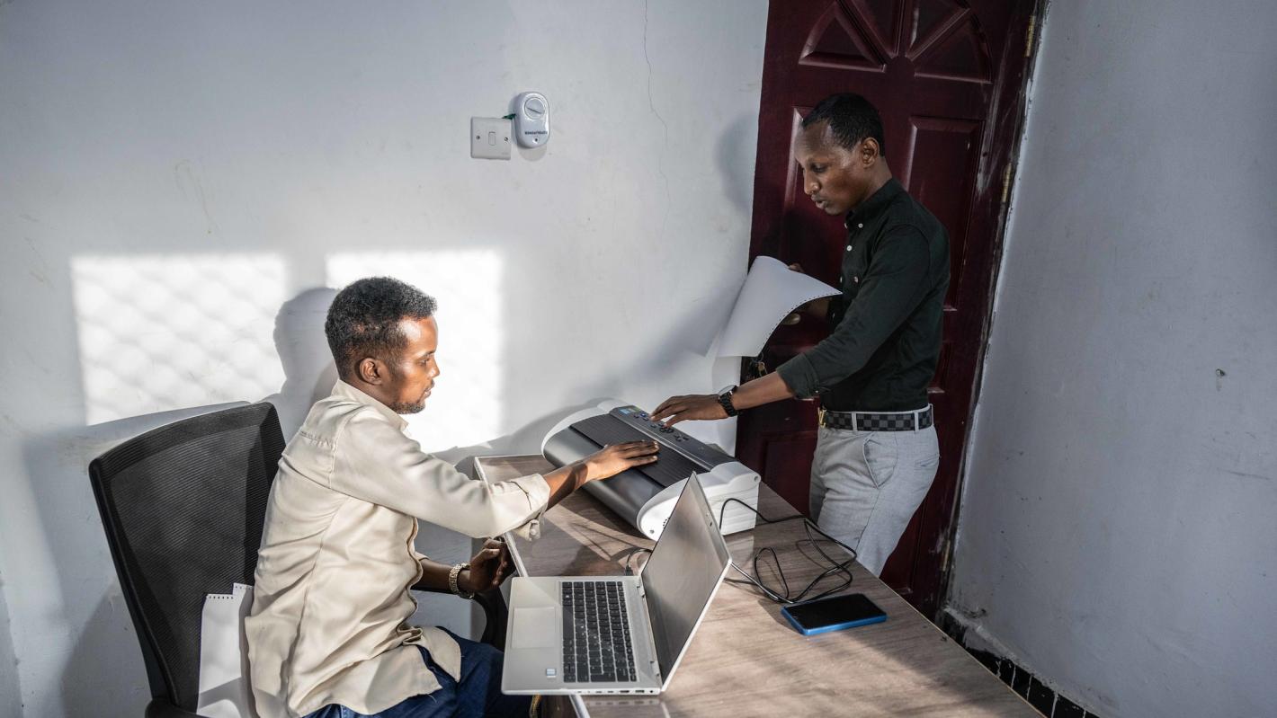 A photo of Abdirahman Mohamud Kulane and Abdulkadir Mohamed Abudllahi operate the UDHAN braille machine at their office in Mogadishu after completing a week-long of intensive training on braille machines in Kampala, Uganda.