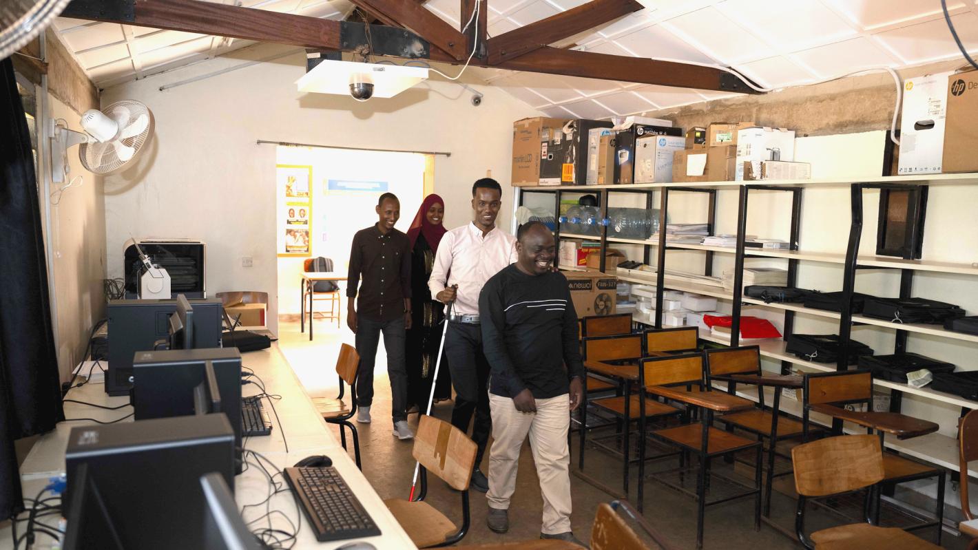 A photo of Kyebagadha Binsali, the Head of KyU Hi-Techn Center, guides UDHAN team members to the visual training center in the Faculty of Special Needs, where they will begin their training on braille production and digital inclusion.