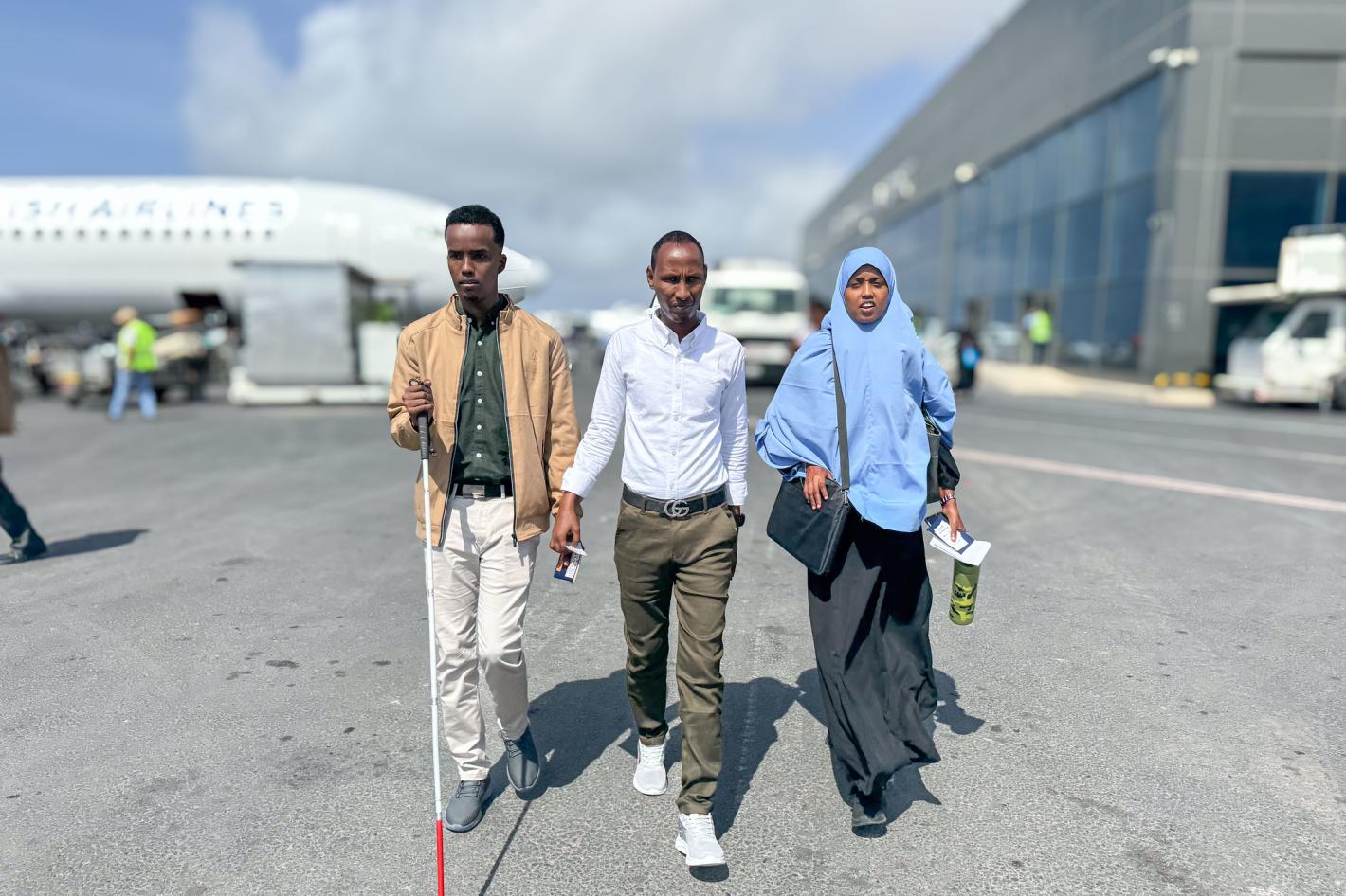 A photo of Abdirahman Mohamud Kulane (left), Abdulkadir Mohamed Abdullahi (middle), and Hamdi Hussein Osman (right), prepare to departure from Adan Adde airport on their way to kampala to participate in a week-long training on braille production and digital inclusion.