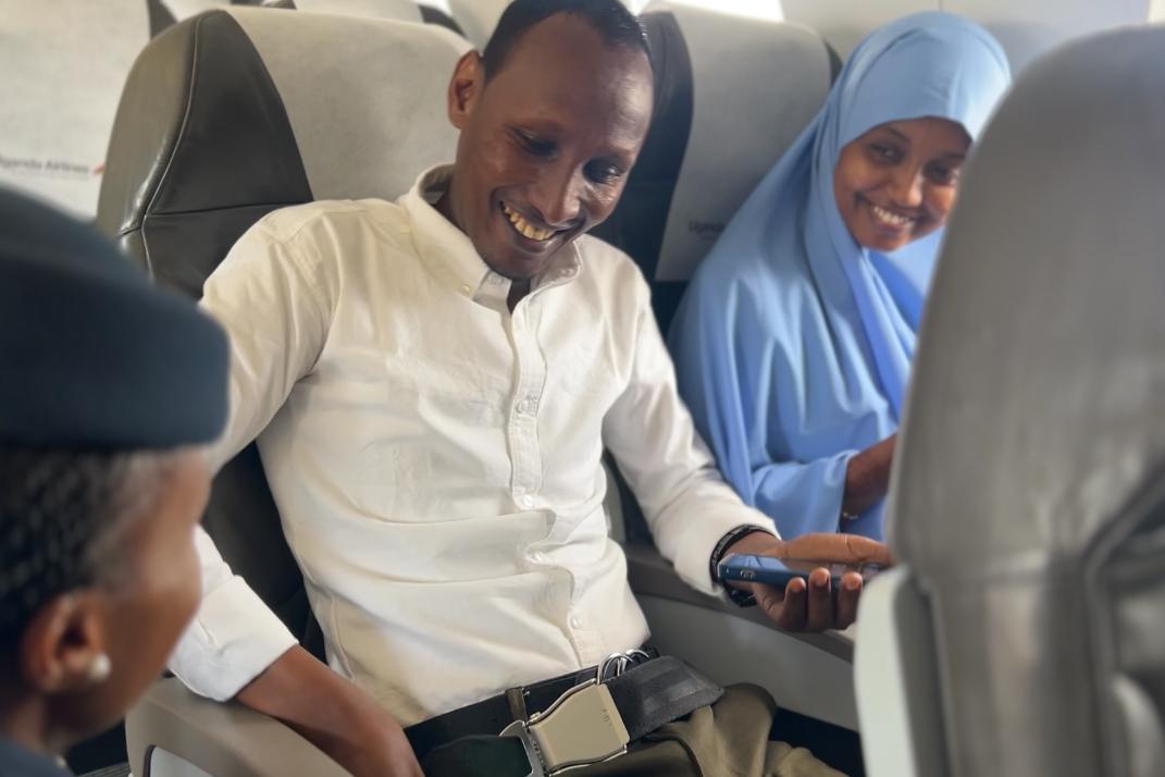 A photo of Mr. Abdullahi and Ms. Osman speaking with a flight attendant.