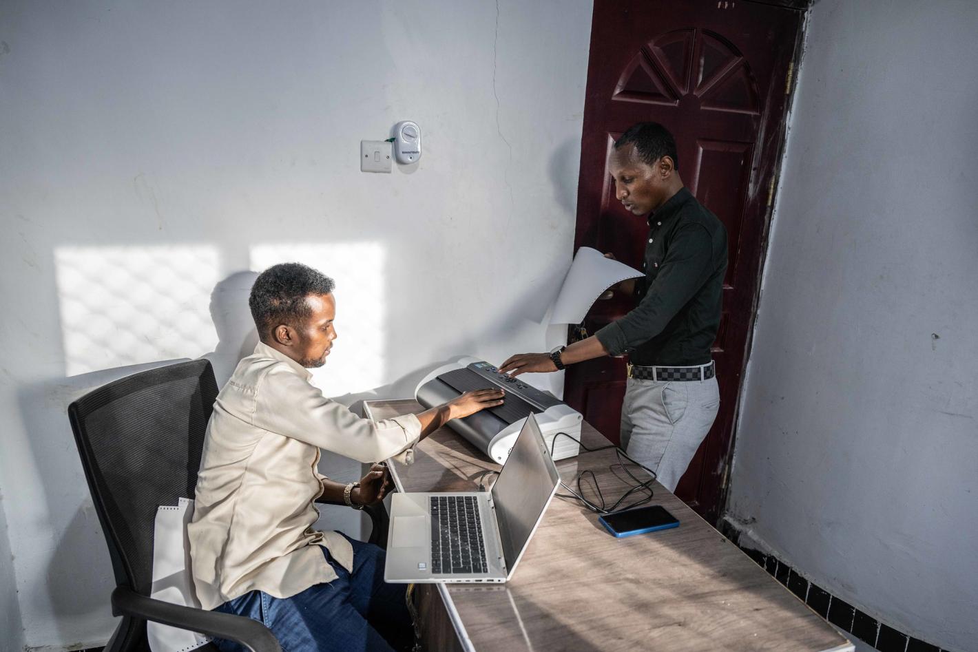 A photo of Abdirahman Mohamud Kulane and Abdulkadir Mohamed Abudllahi operate the UDHAN braille machine at their office in Mogadishu after completing a week-long of intensive training on braille machines in Kampala, Uganda.