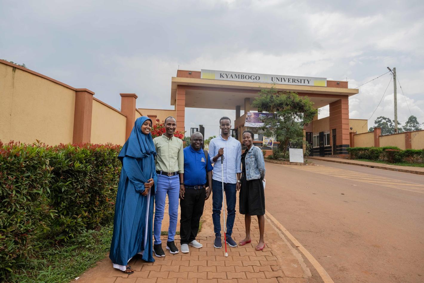 Kyebagadha Binsali, the Head of KyU Hi-Techn Center, and UDHAN team members pose for a group photo at the main gate of KyU in Kampala, Uganda.