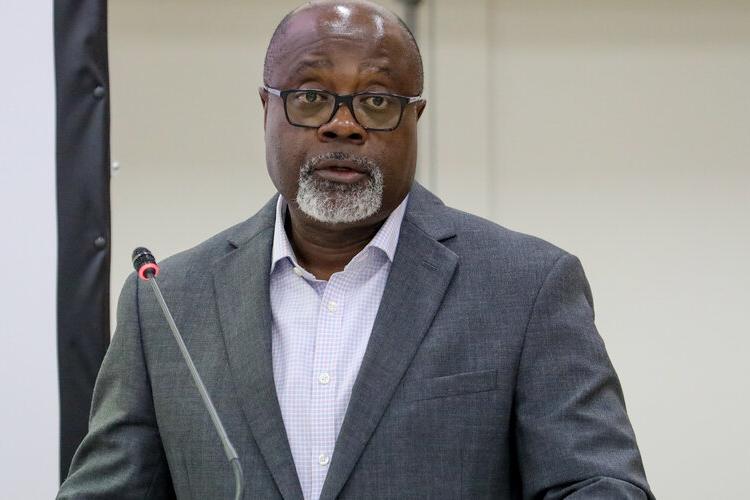A man standing at a lectern and addressing the audience with a microphone.