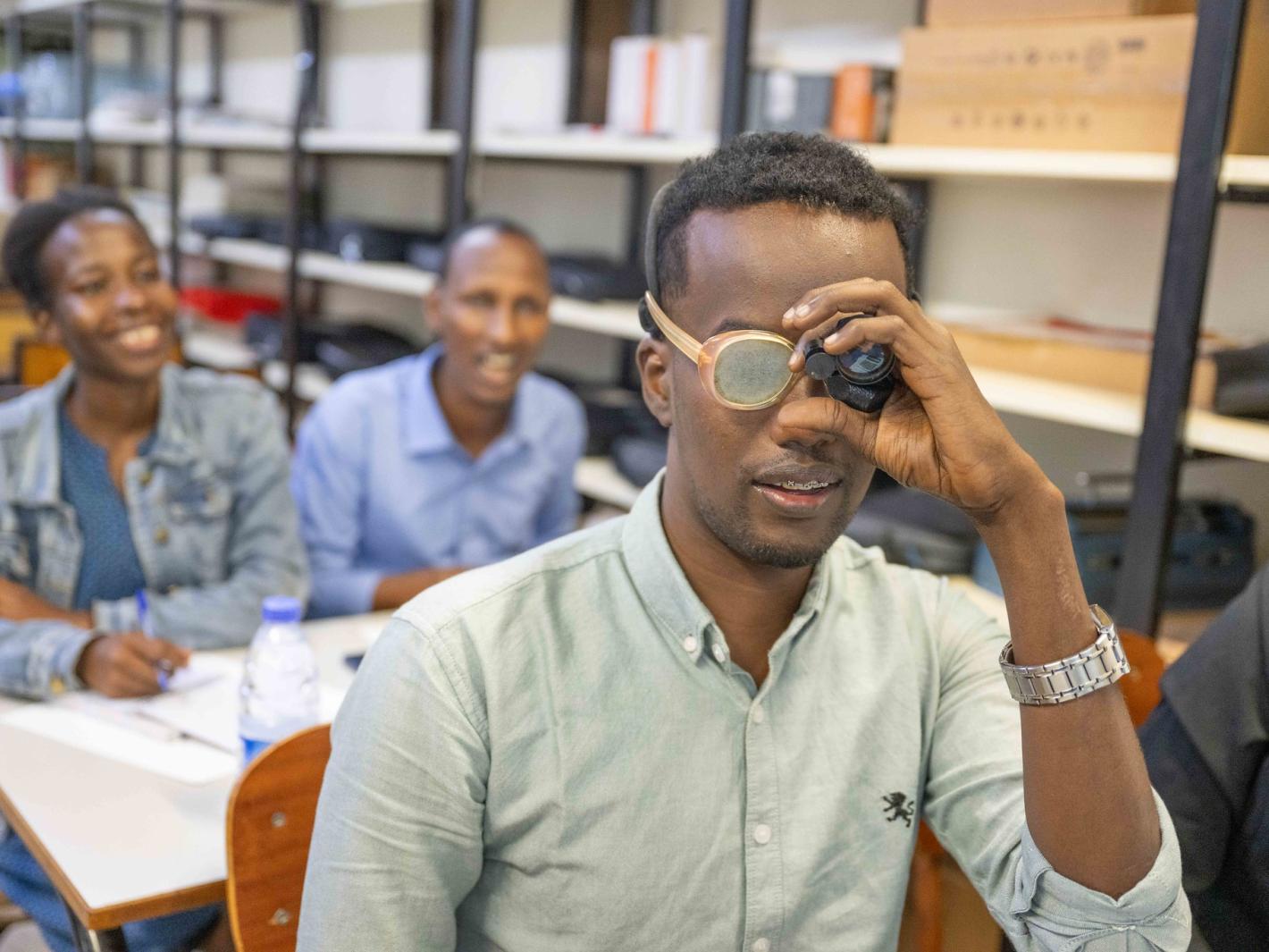 Photo of Mr. Kulane tries on a pair of low-vision glasses for the first time.