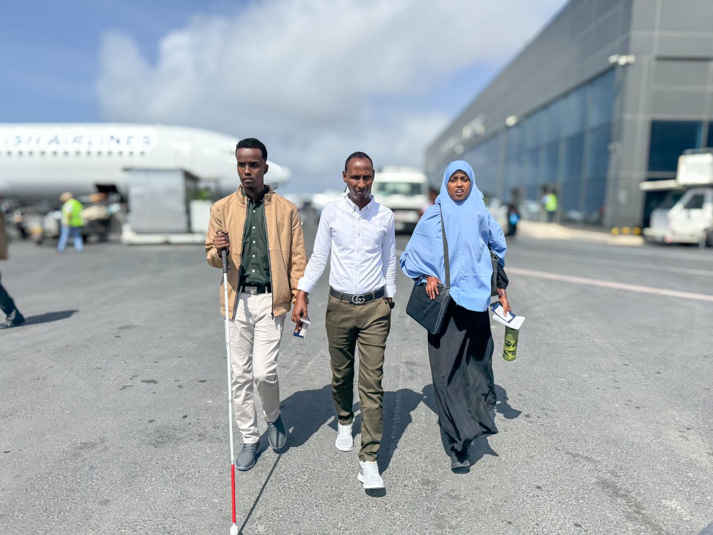 A photo of Abdirahman Mohamud Kulane (left), Abdulkadir Mohamed Abdullahi (middle), and Hamdi Hussein Osman (right), prepare to departure from Adan Adde airport on their way to kampala to participate in a week-long training on braille production and digital inclusion.