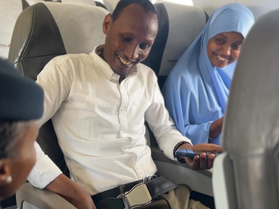 A photo of Mr. Abdullahi and Ms. Osman speaking with a flight attendant.