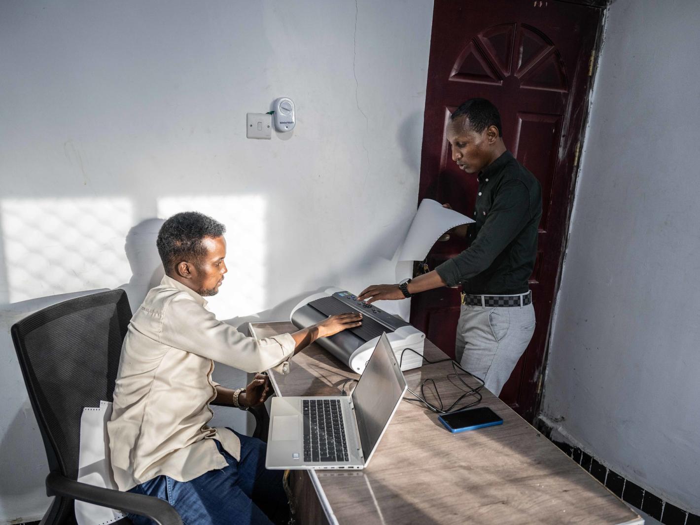 A photo of Abdirahman Mohamud Kulane and Abdulkadir Mohamed Abudllahi operate the UDHAN braille machine at their office in Mogadishu after completing a week-long of intensive training on braille machines in Kampala, Uganda.