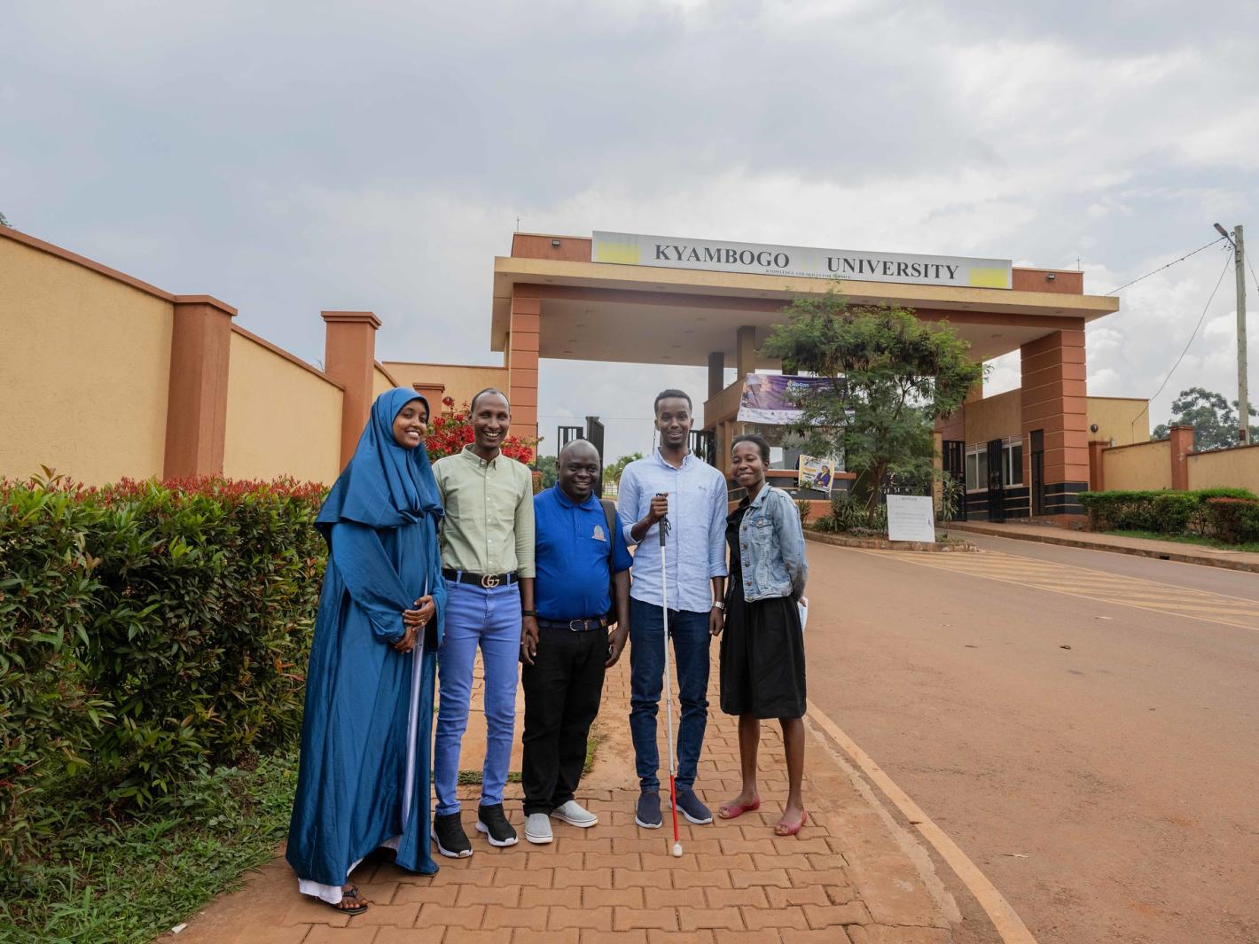 Kyebagadha Binsali, the Head of KyU Hi-Techn Center, and UDHAN team members pose for a group photo at the main gate of KyU in Kampala, Uganda.