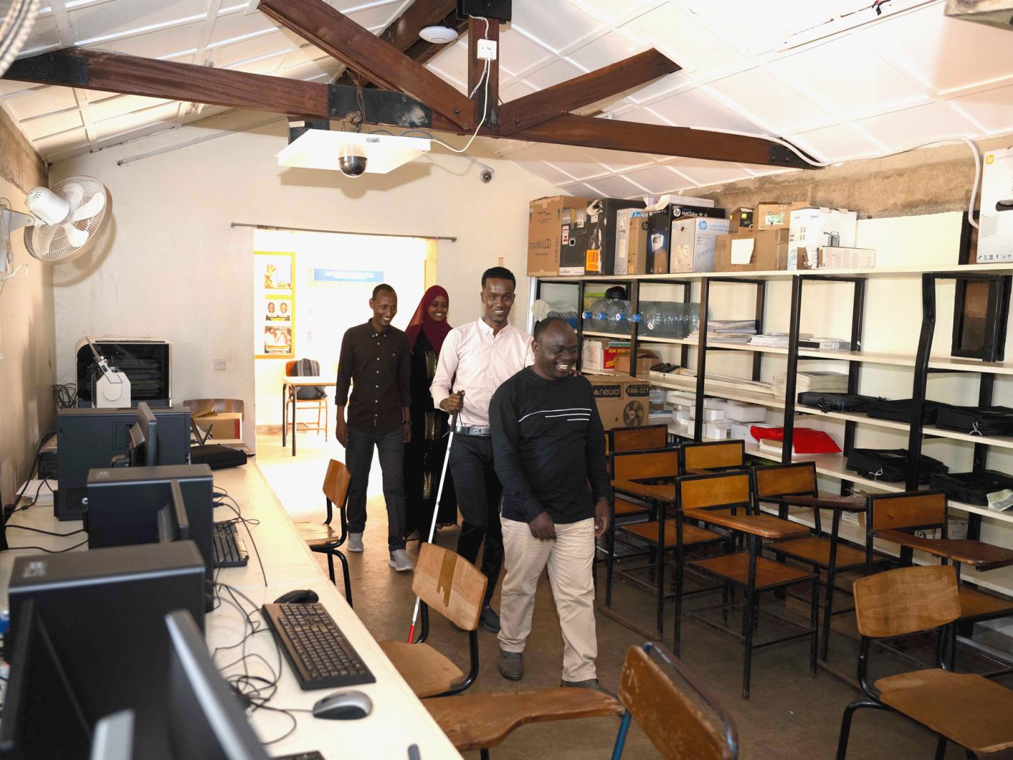 A photo of Kyebagadha Binsali, the Head of KyU Hi-Techn Center, guides UDHAN team members to the visual training center in the Faculty of Special Needs, where they will begin their training on braille production and digital inclusion.