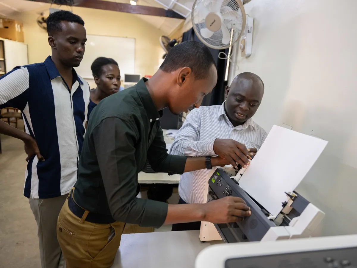 A photo of Abdulkadir Mohamed Abdullahir examines one of the braille machines during a training on braille production and digital inclusion at KyU Hi-Techn Center in Kampala, Uganda.